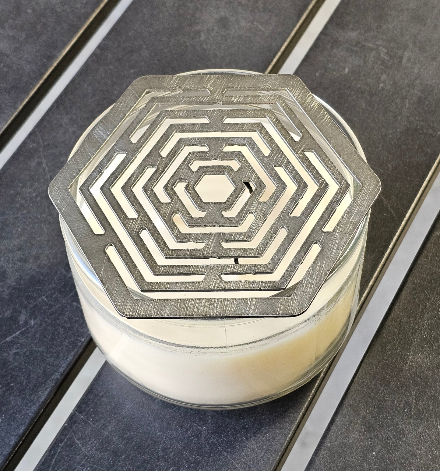 Hexagon stainless steel candle topper on jar candle – modern geometric candle accessory.
