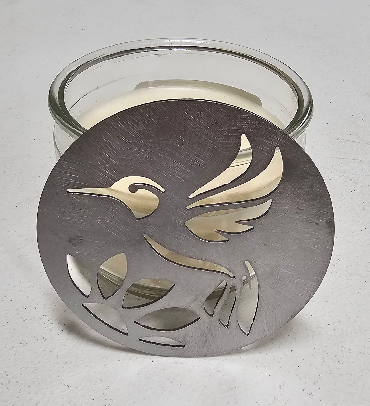 Hummingbird metal candle topper on 3-wick candle with cutout leaf design
