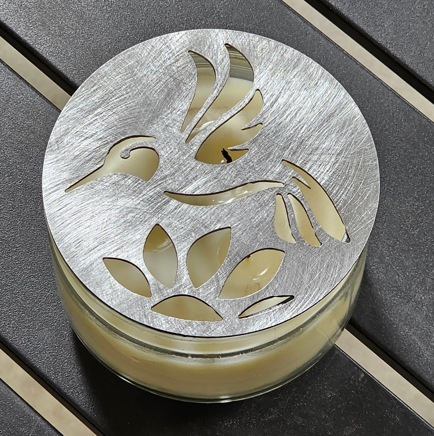 Hummingbird metal candle topper on 3-wick candle with cutout leaf design