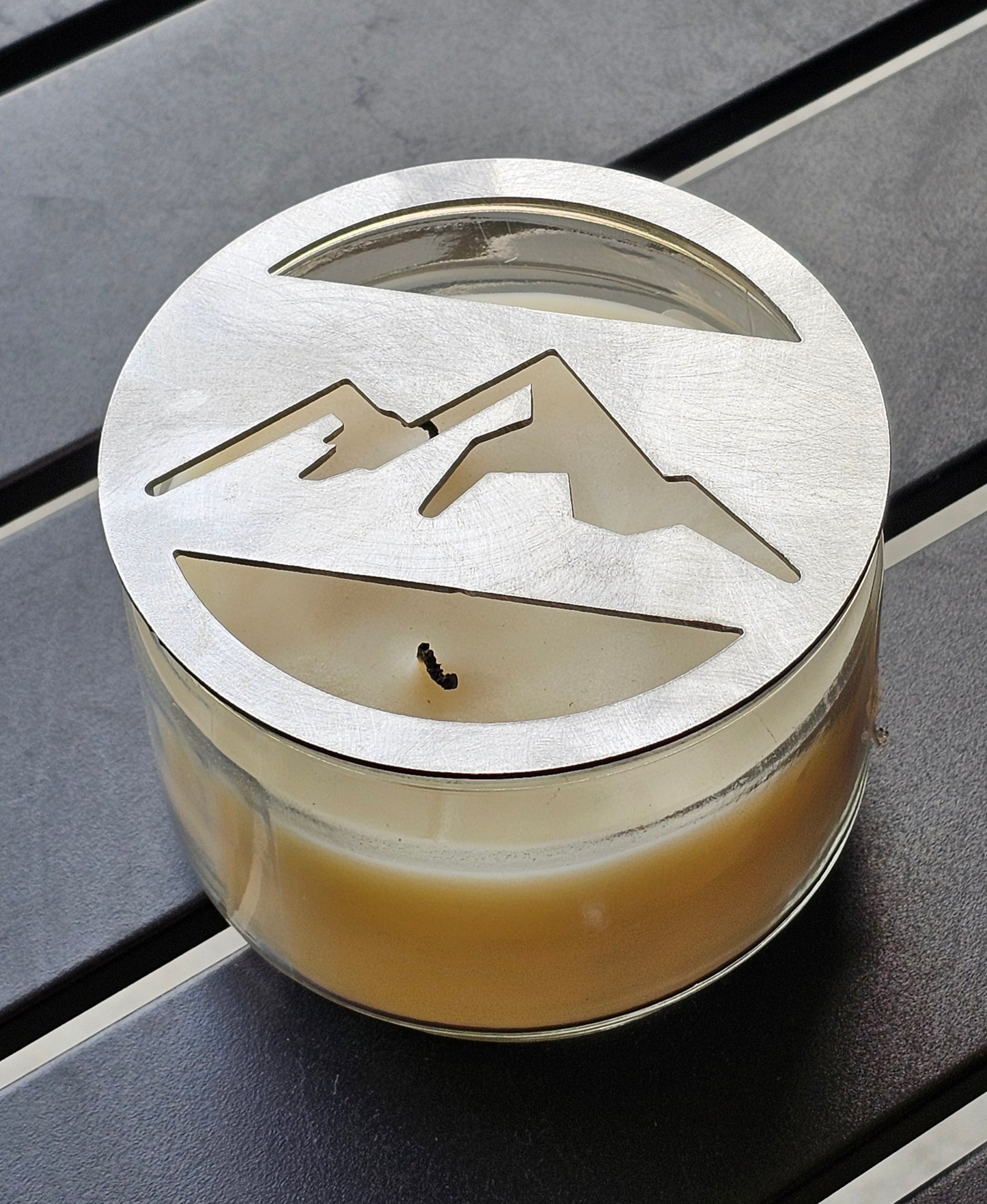 Mountain metal candle topper placed on white jar candle