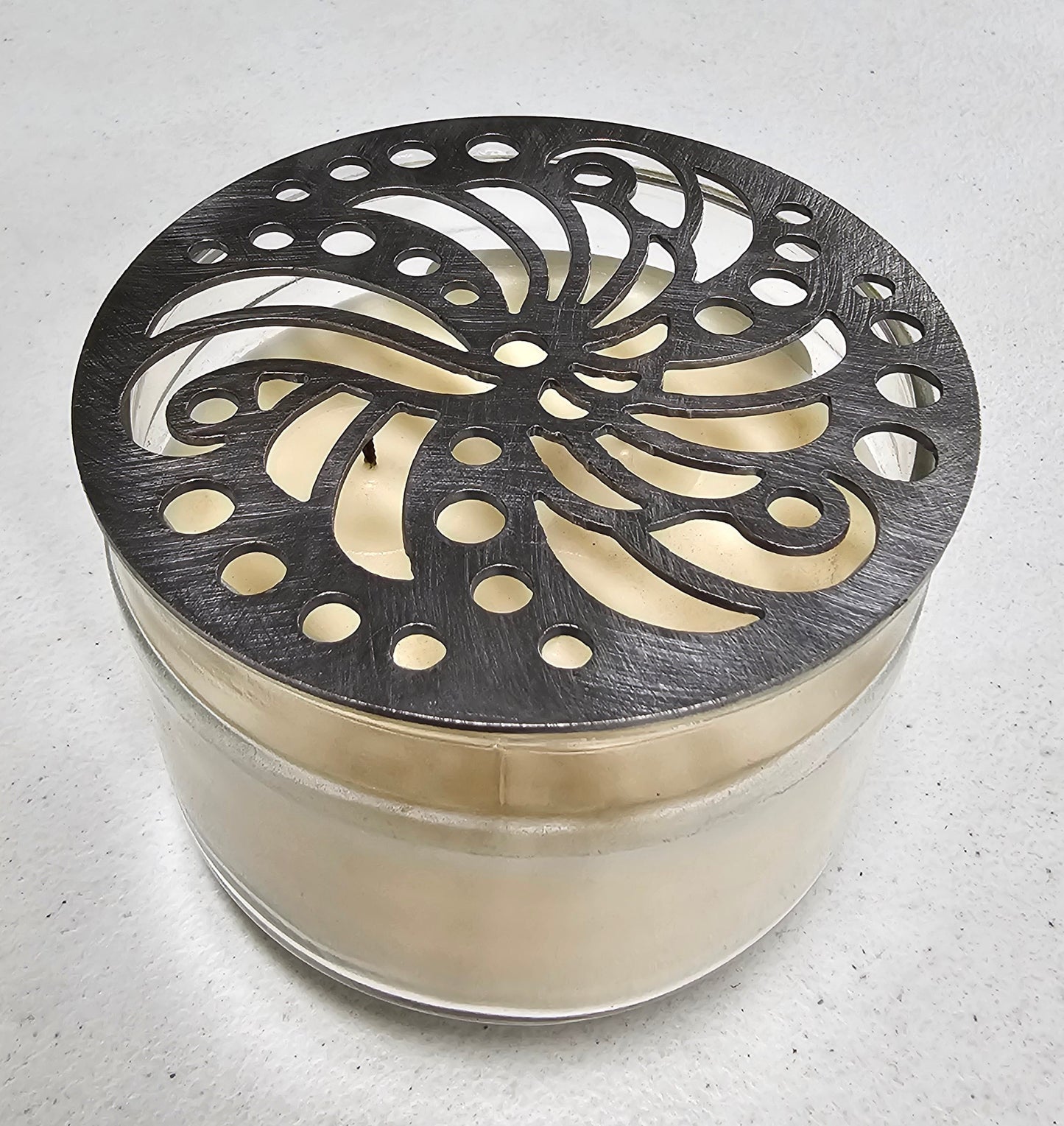 Luxury candle accessory with intricate cutout design casting soft light pattern.