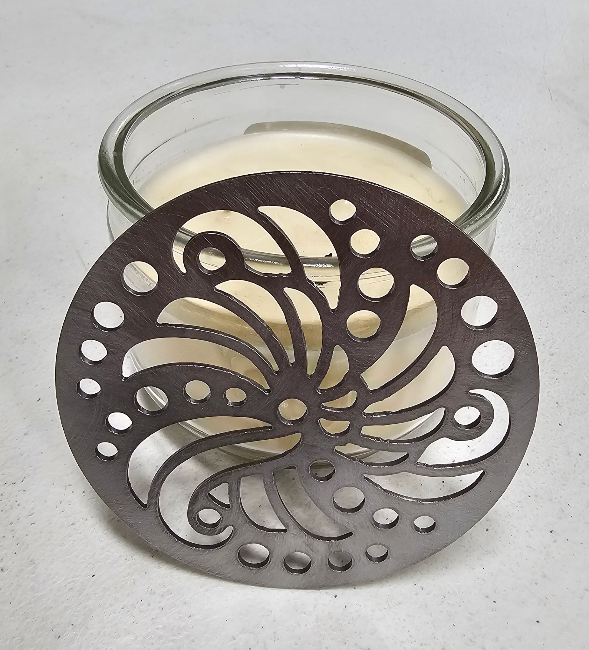 Brushed metal candle lid showing detailed swirl design of Sundara Candle Topper.