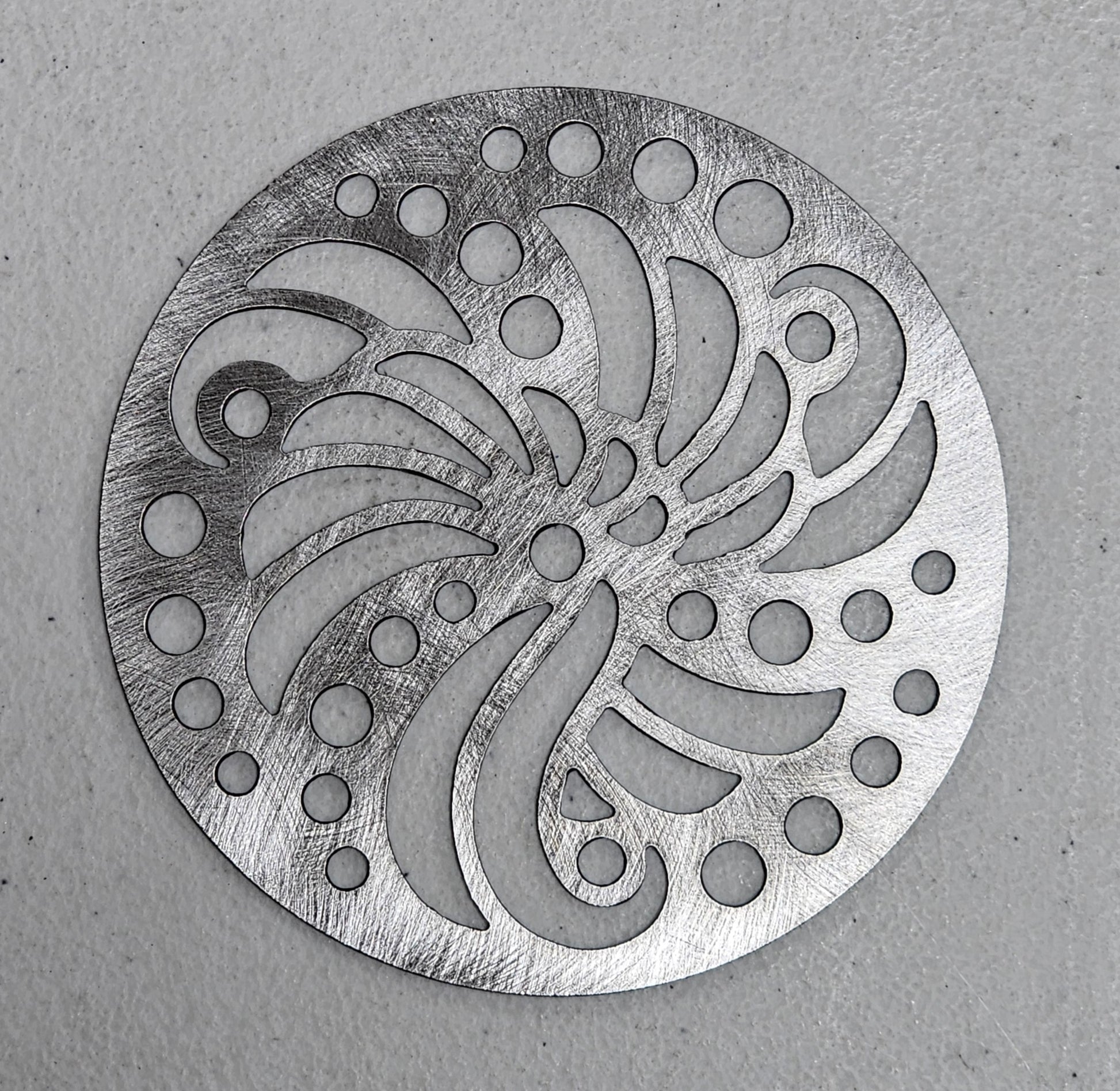 Brushed metal candle lid showing detailed swirl design of Sundara Candle Topper.