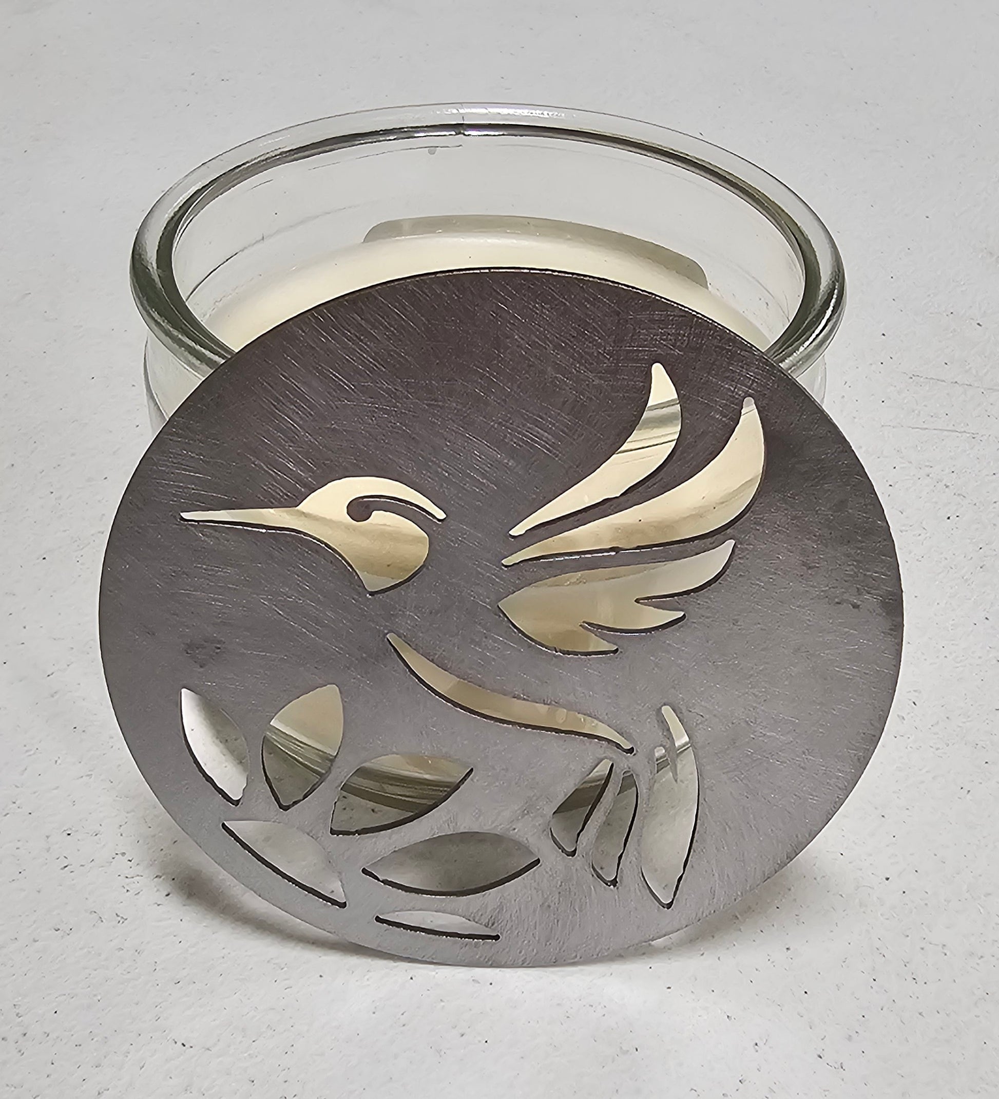 Hummingbird metal candle topper on 3-wick candle with cutout leaf design