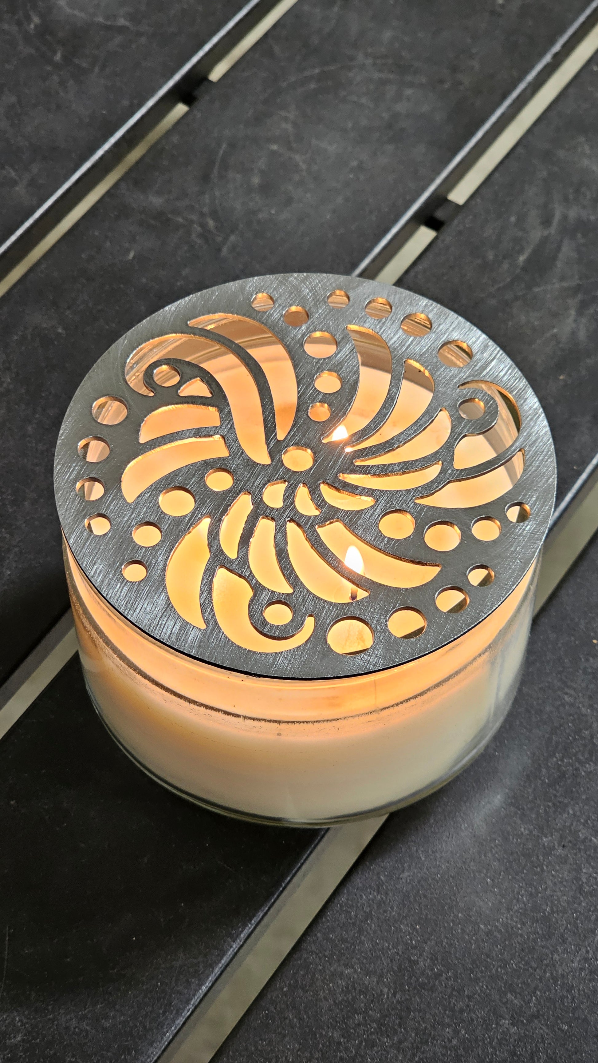 Luxury candle accessory with intricate cutout design casting soft light pattern.