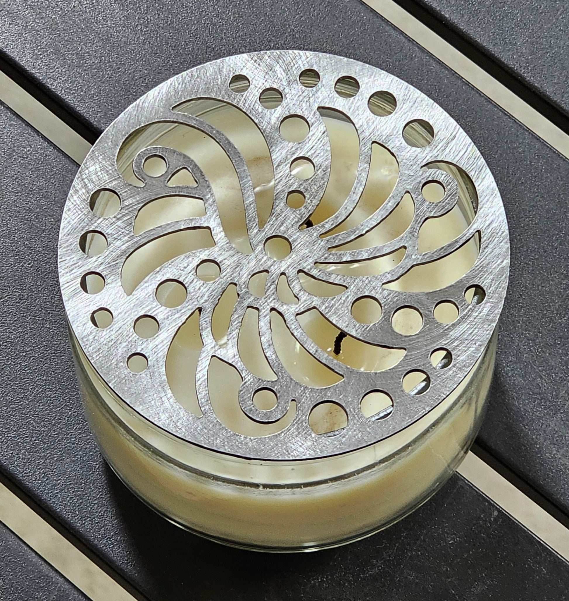 Luxury candle accessory with intricate cutout design casting soft light pattern.