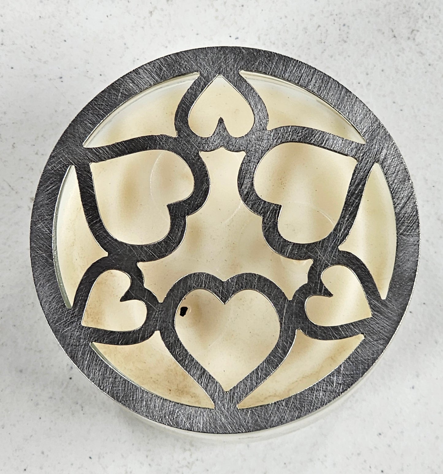 Tangled Hearts metal candle topper featuring intertwined heart design on a lit jar candle