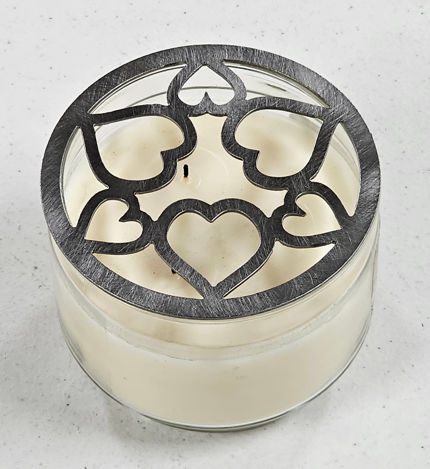 Tangled Hearts metal candle topper featuring intertwined heart design on a lit jar candle