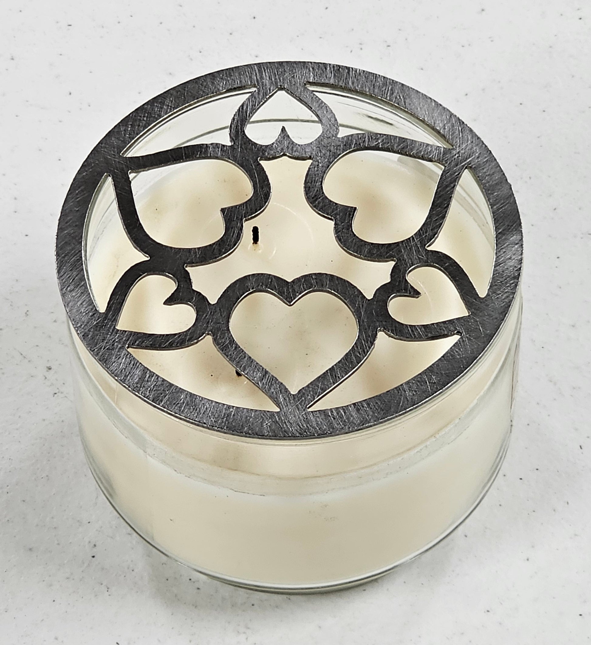 Tangled Hearts metal candle topper featuring intertwined heart design on a lit jar candle
