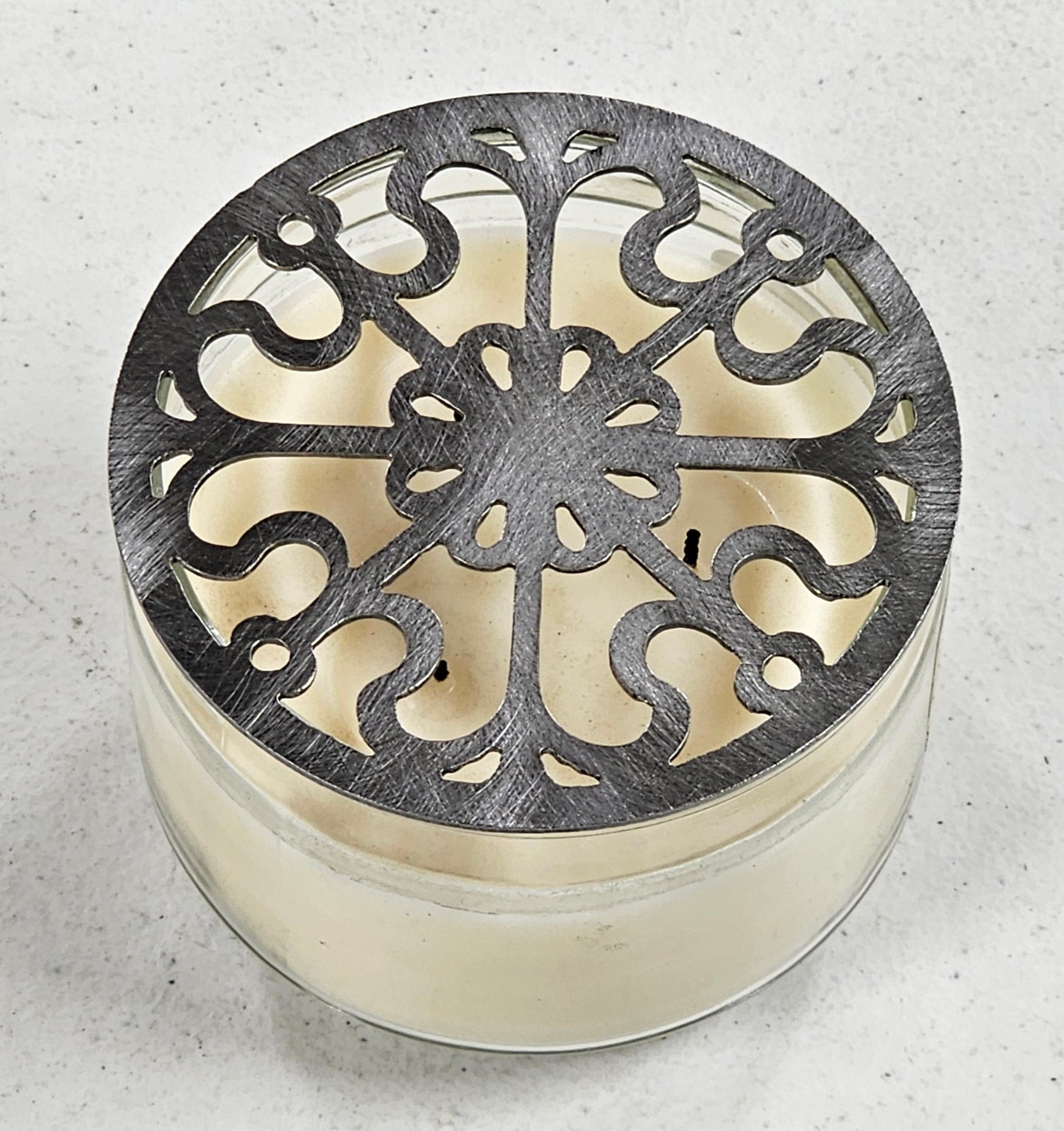 Victorian Scroll metal candle topper on a lit jar candle featuring ornate vintage scrollwork design