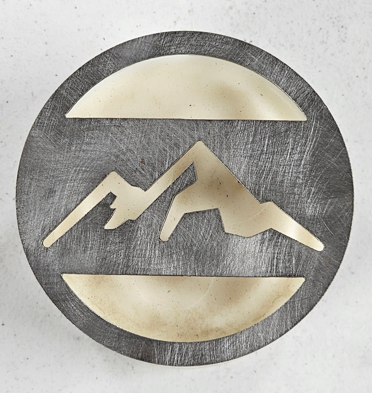Mountain metal candle topper placed on white jar candle