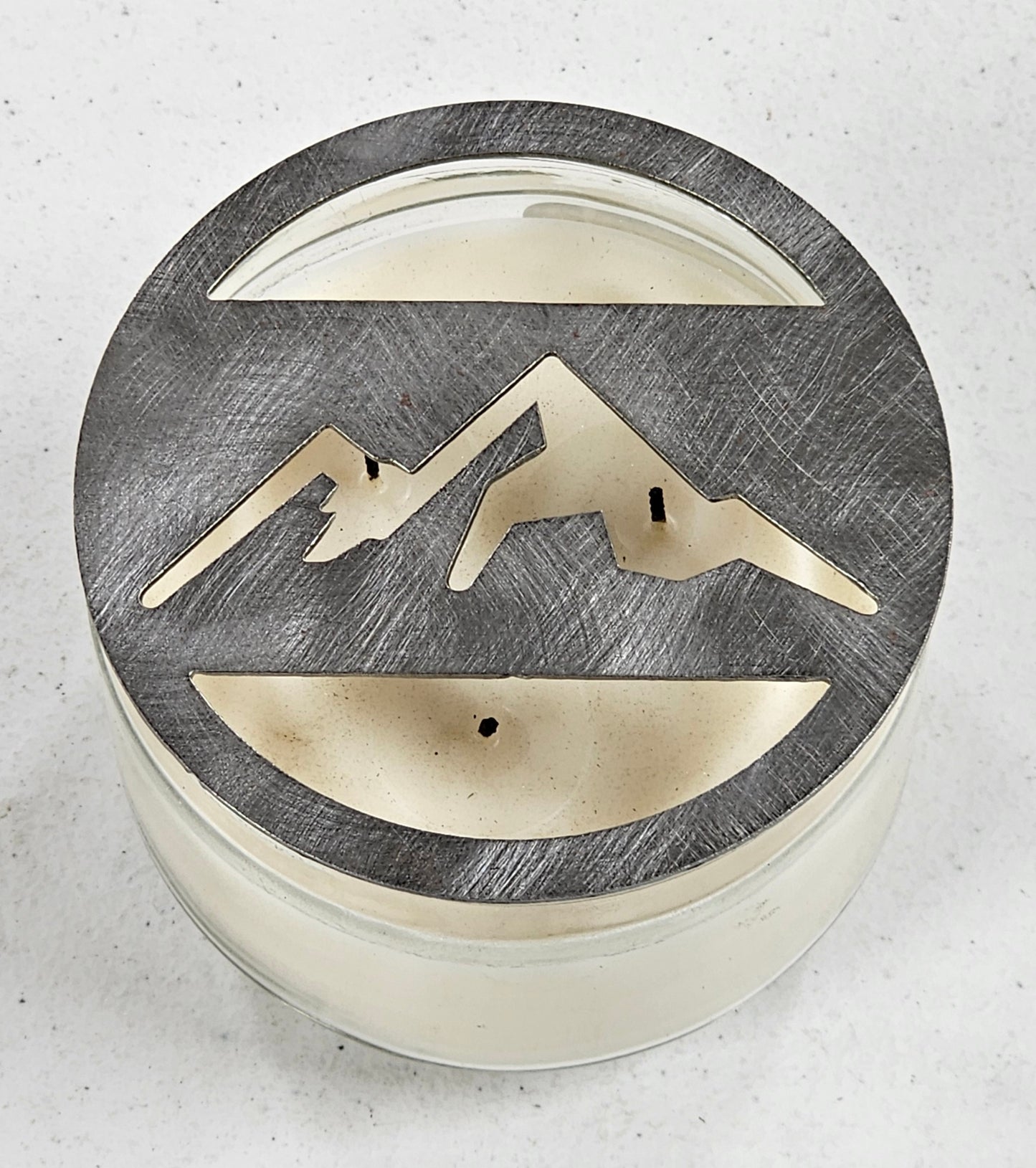 Mountain metal candle topper placed on white jar candle