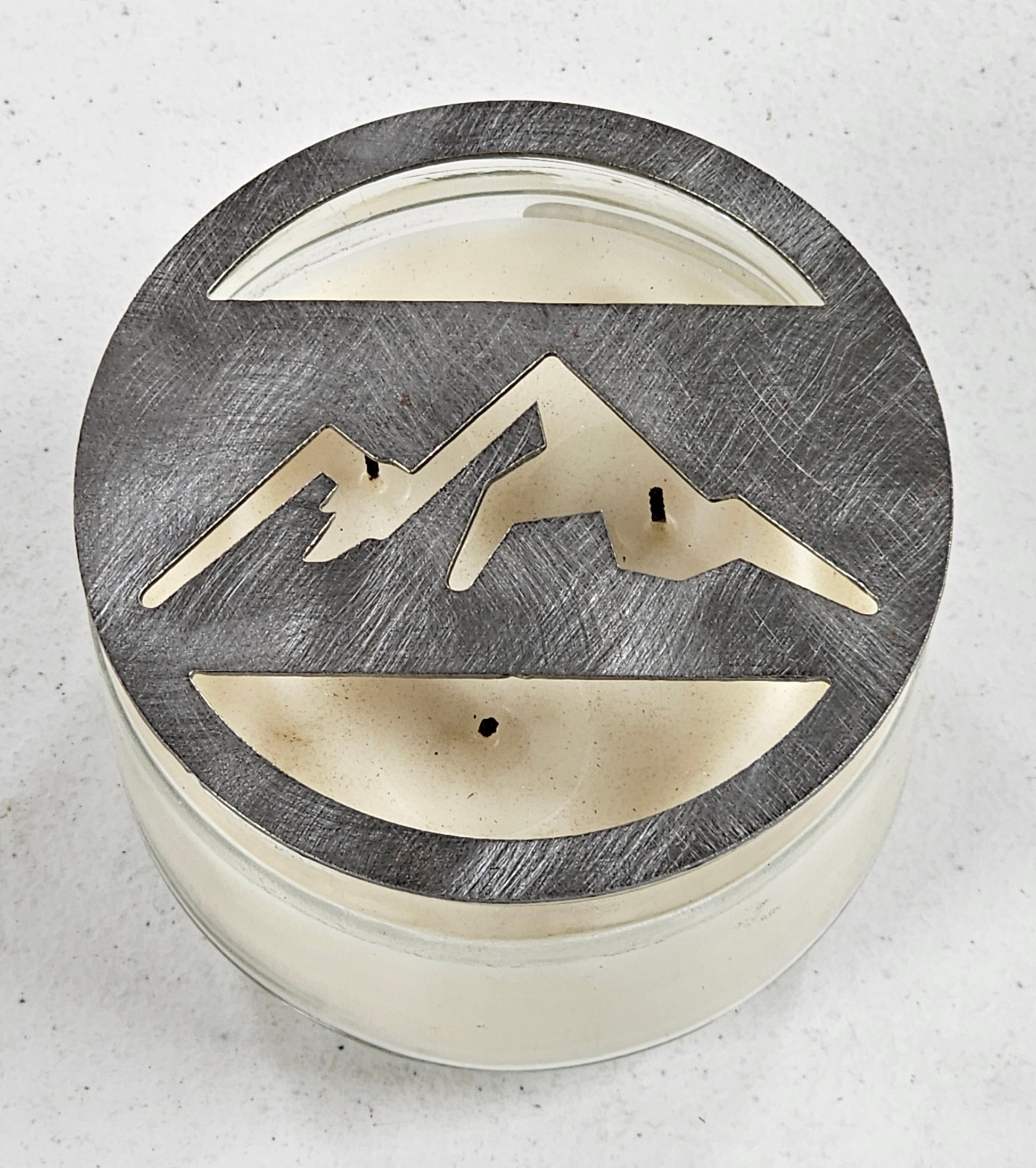 Mountain metal candle topper placed on white jar candle