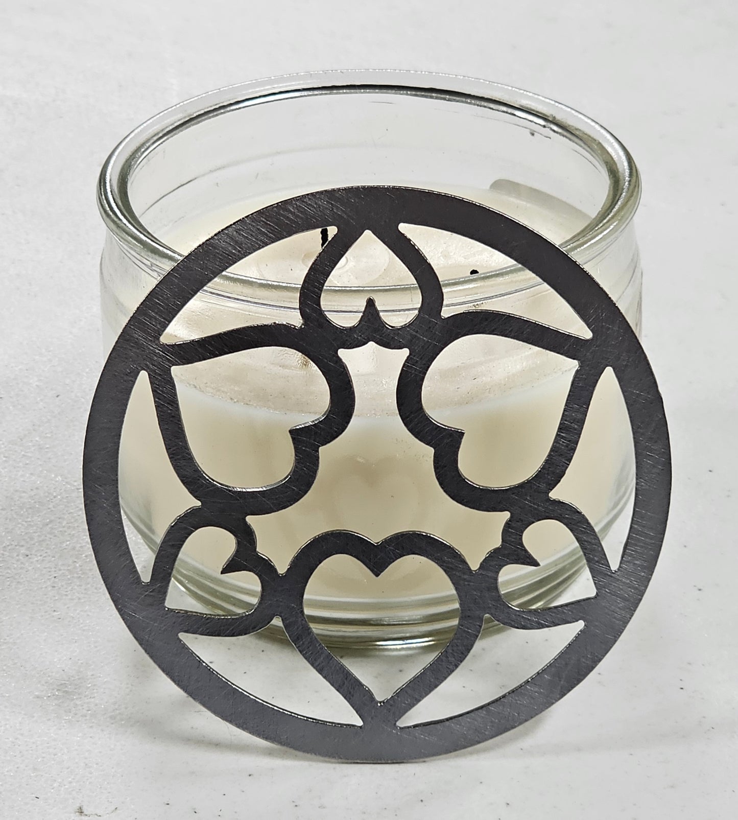 Tangled Hearts metal candle topper featuring intertwined heart design on a lit jar candle