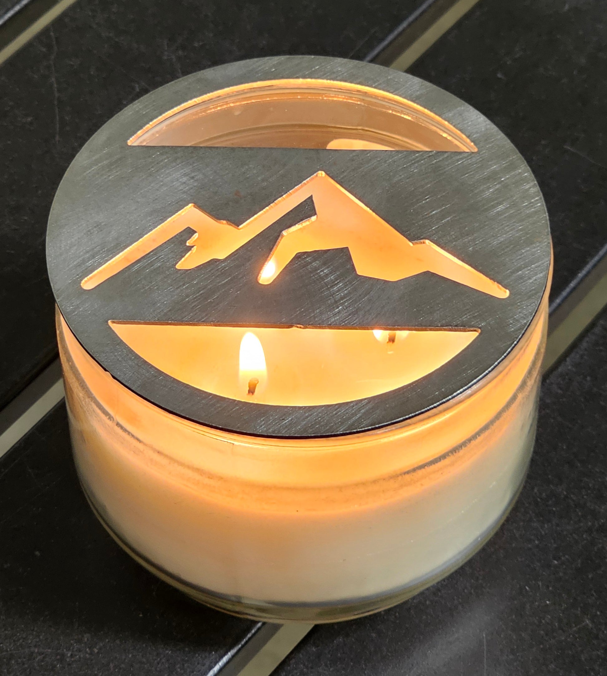 Mountain metal candle topper placed on white jar candle