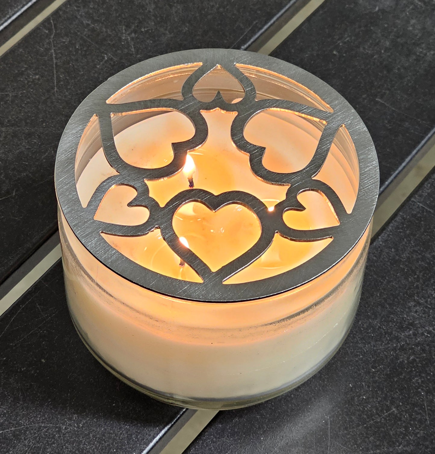 Tangled Hearts metal candle topper featuring intertwined heart design on a lit jar candle