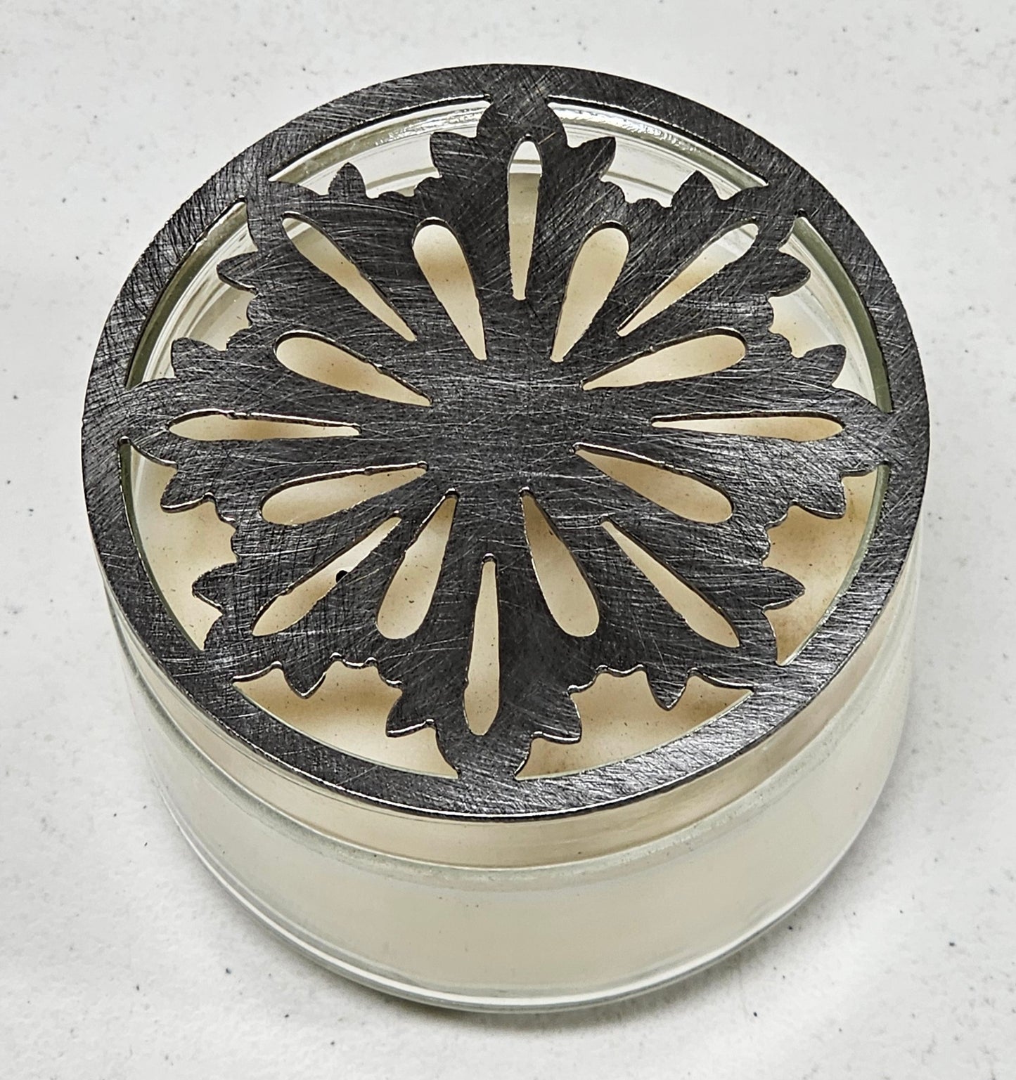 Nordic snowflake metal candle topper placed on white jar candle