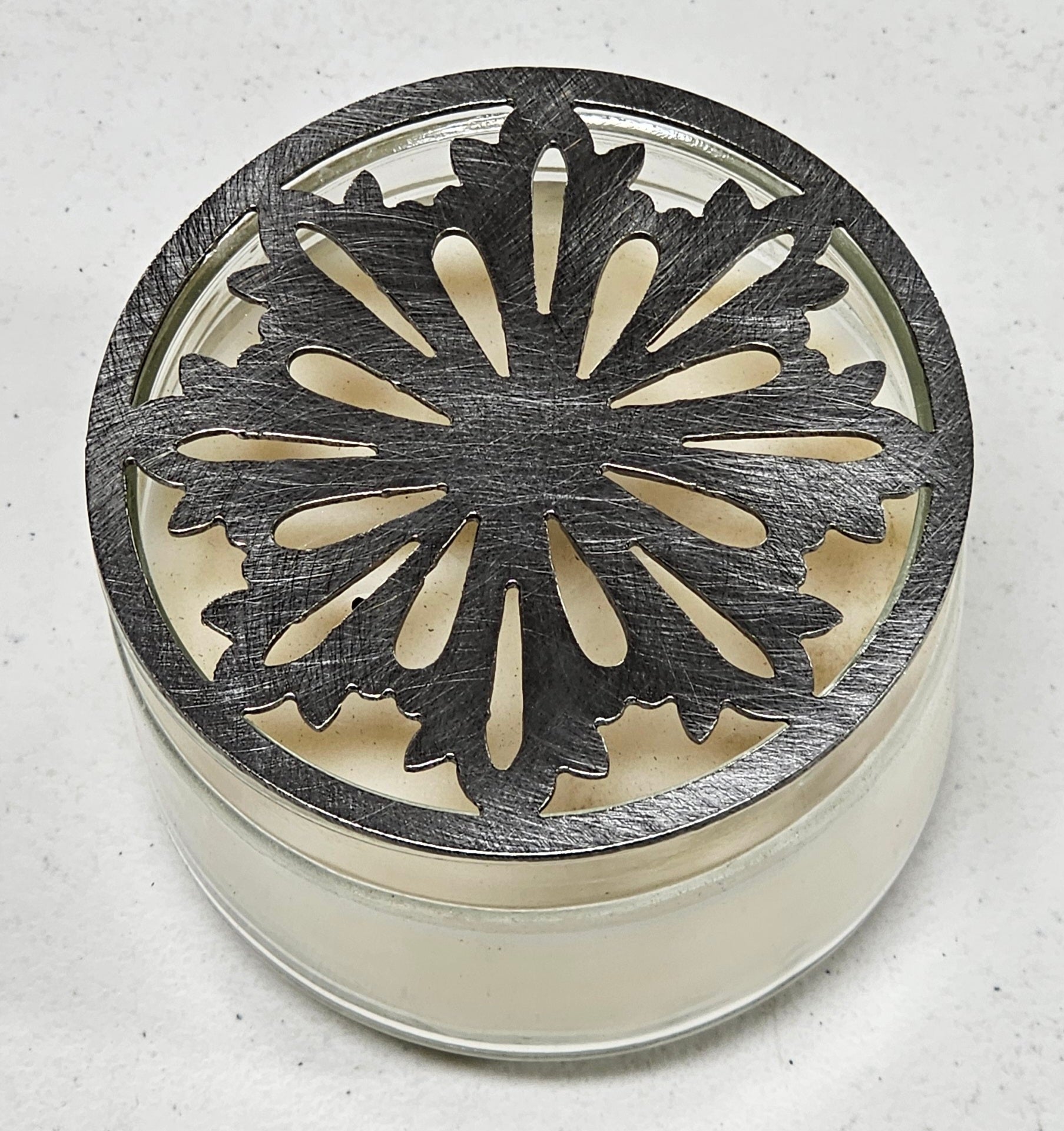 Nordic snowflake metal candle topper placed on white jar candle