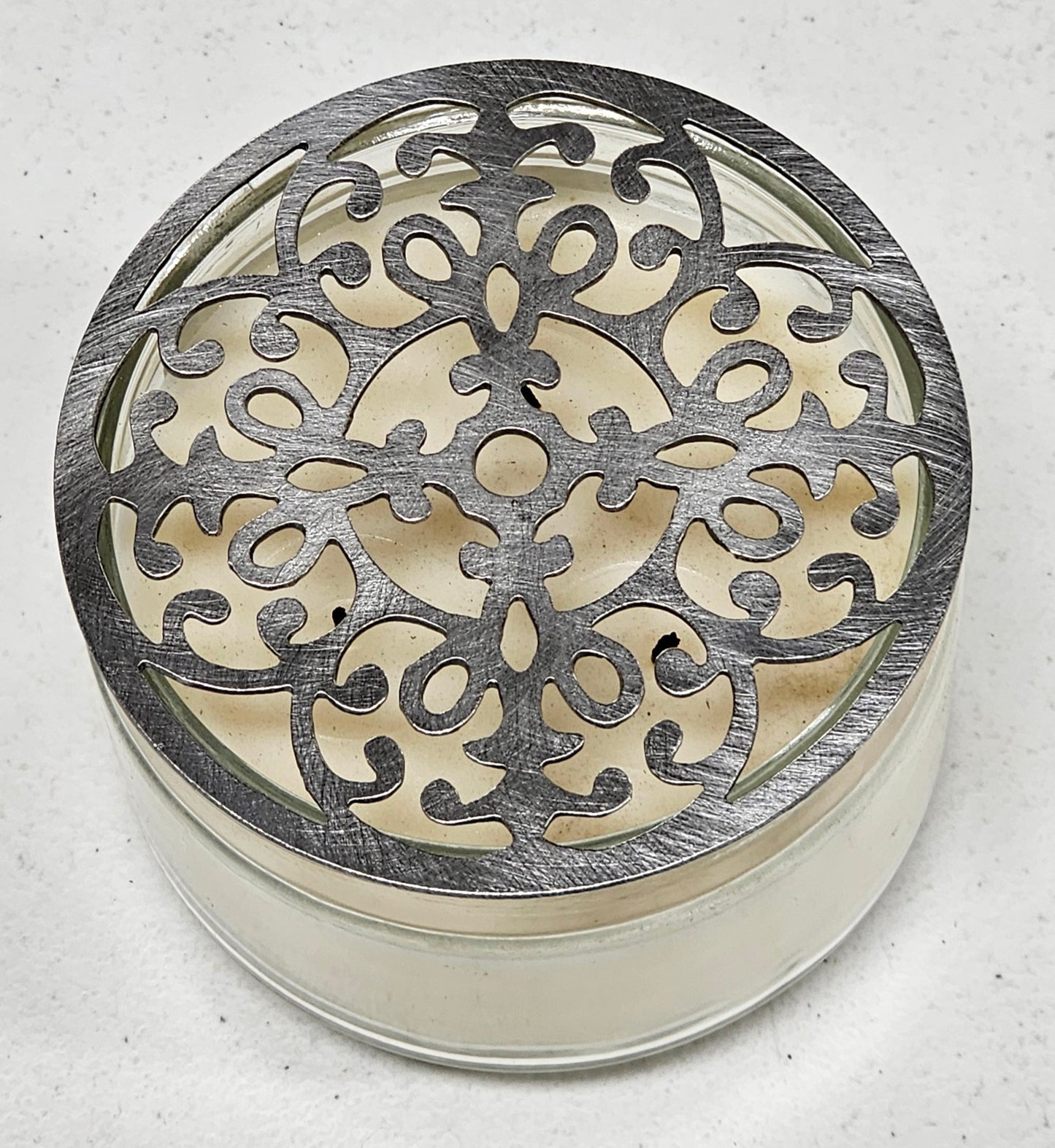 Vintage baroque metal candle topper with ornate scroll design on jar candle
