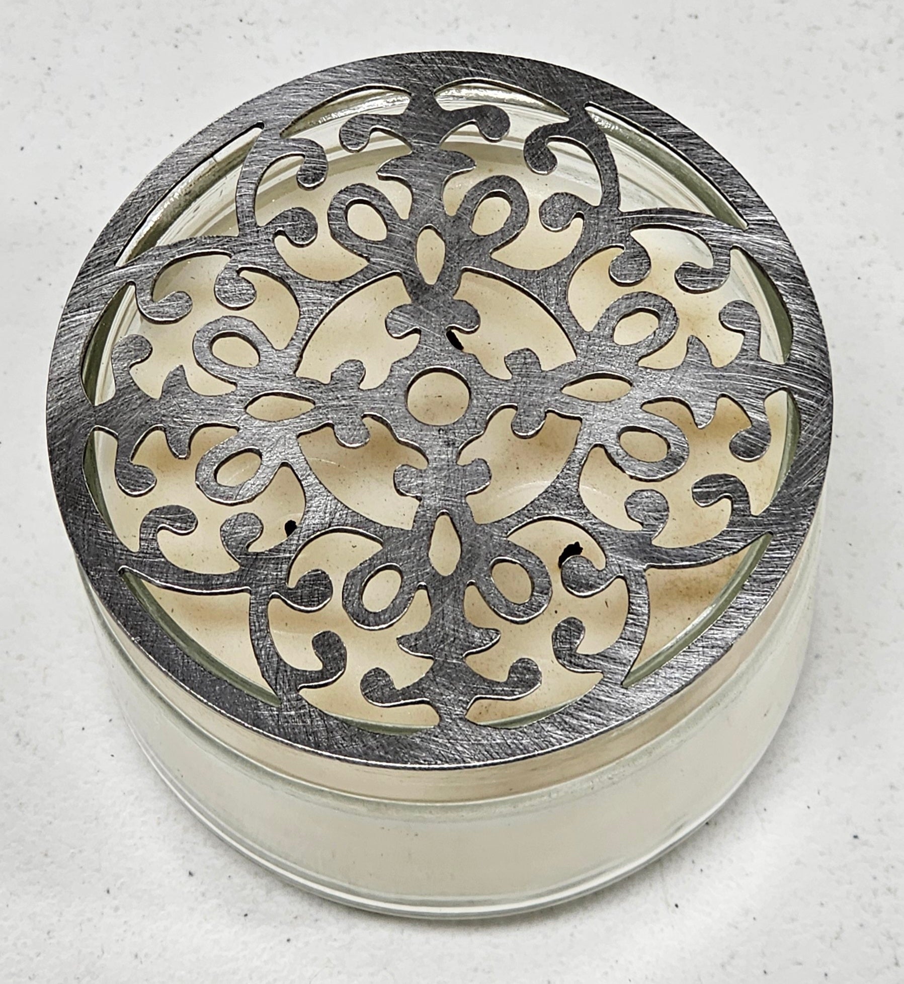 Vintage baroque metal candle topper with ornate scroll design on jar candle