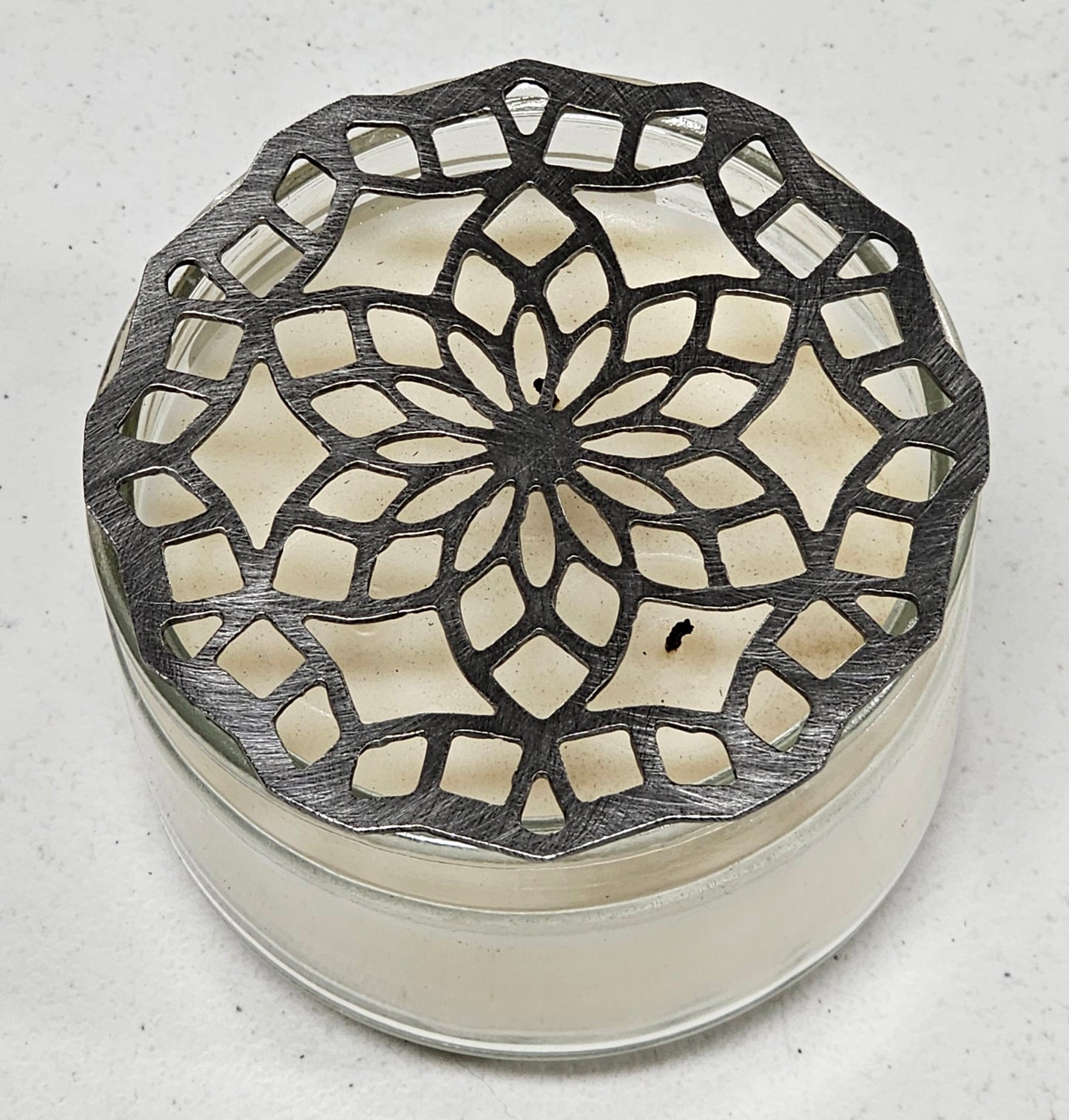 “Floral mandala metal candle topper on jar candle creating even burn and decorative light pattern”