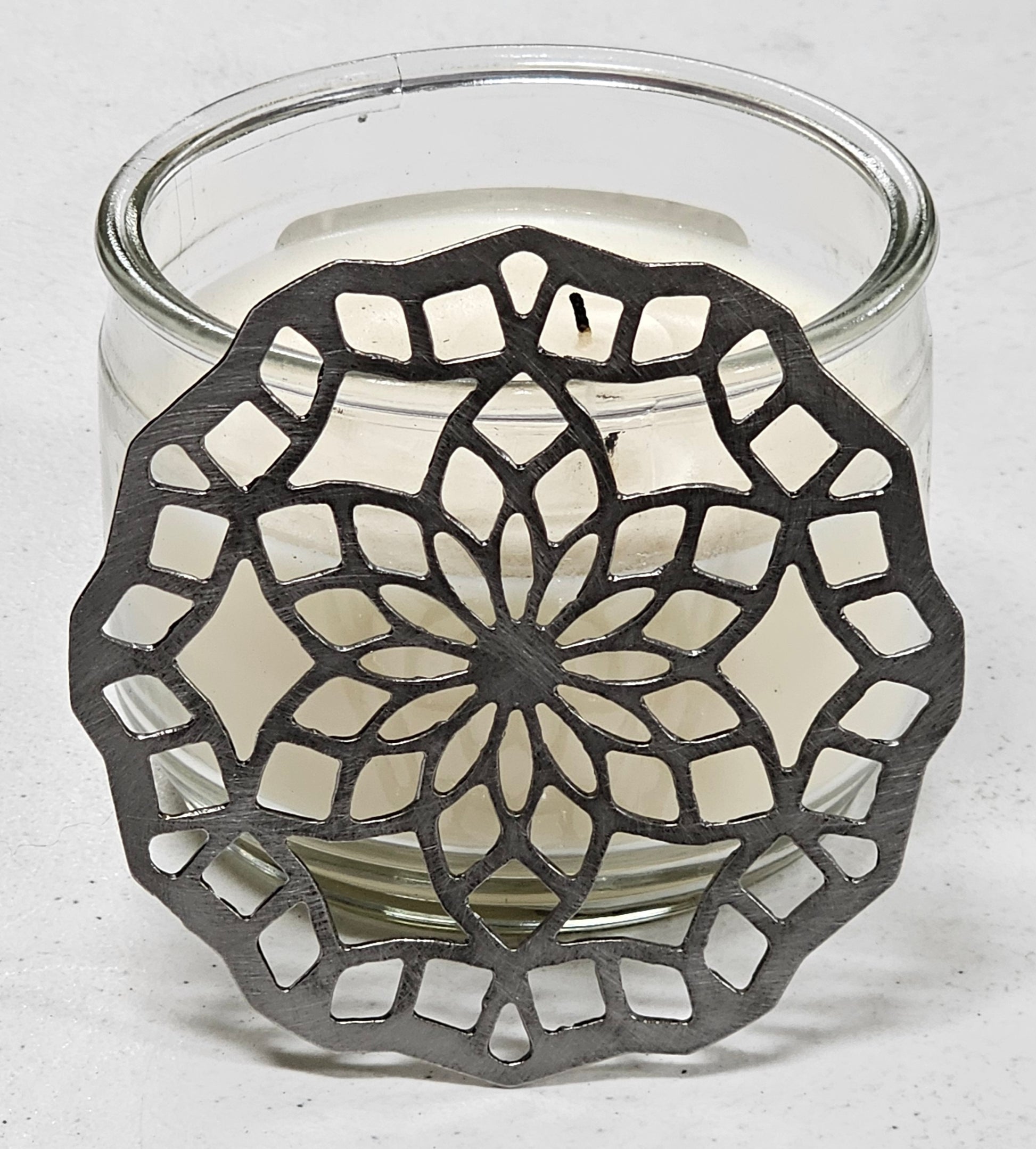 “Floral mandala metal candle topper on jar candle creating even burn and decorative light pattern”