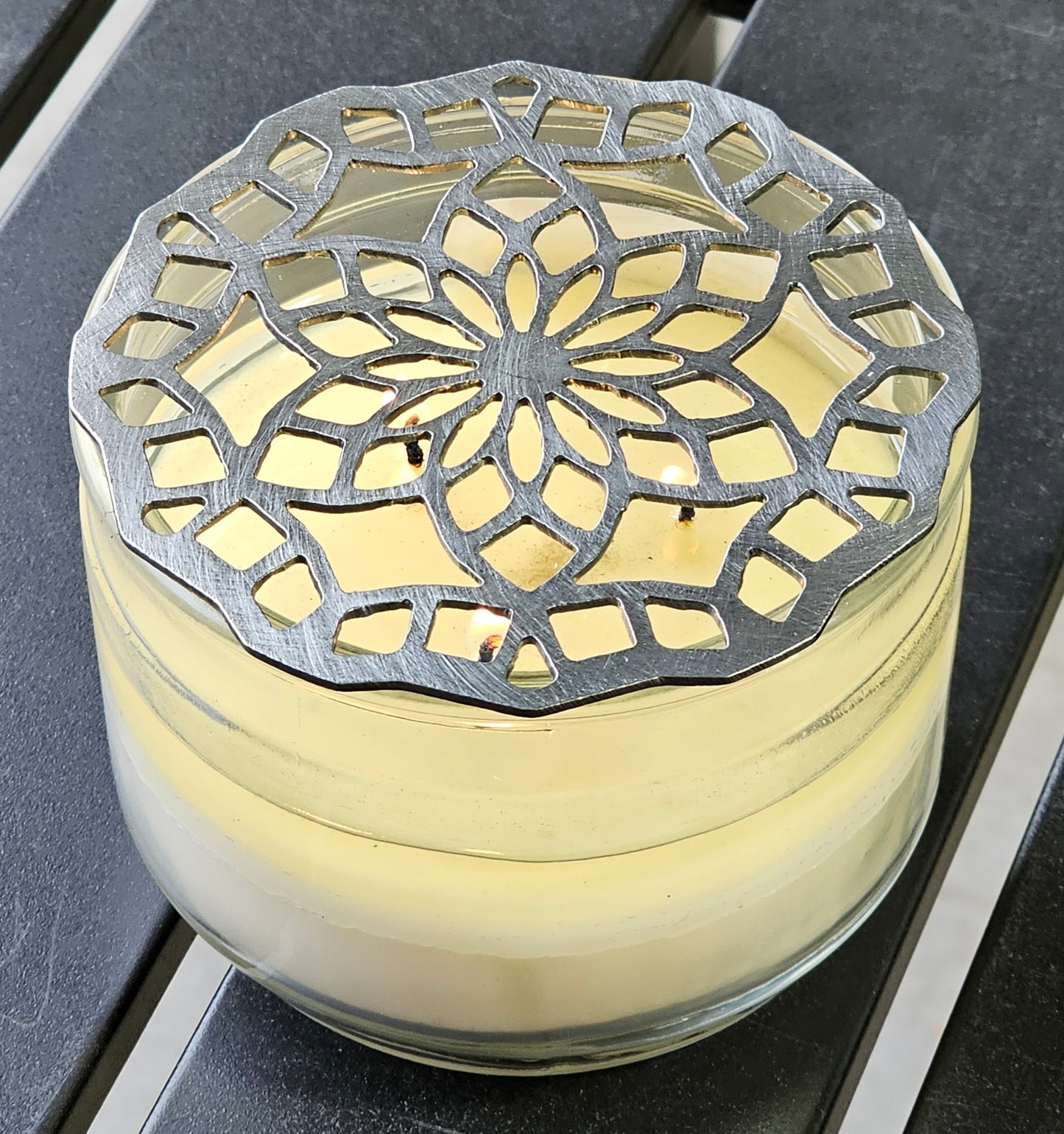 “Floral mandala metal candle topper on jar candle creating even burn and decorative light pattern”
