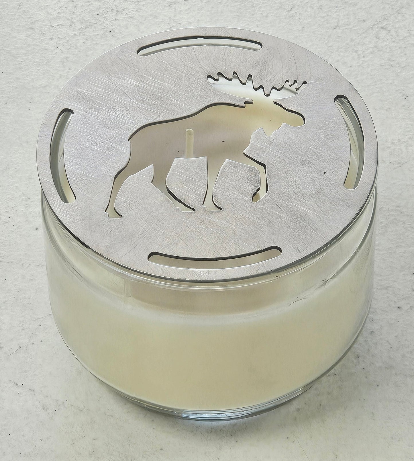 Flat metal candle topper showing moose design resting across top of jar candle
