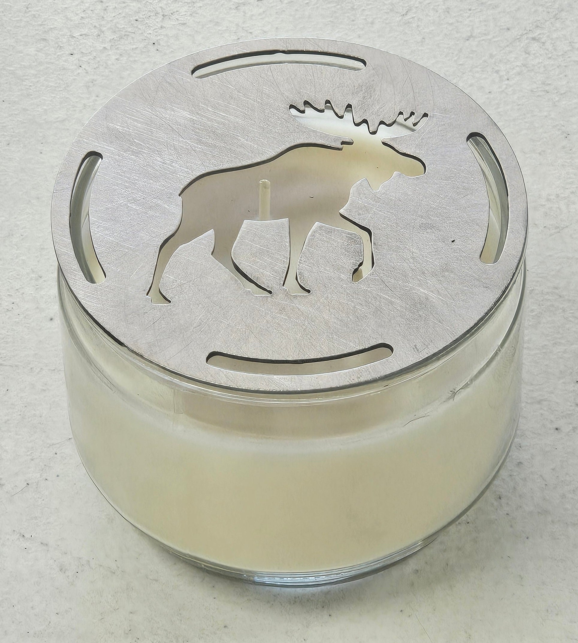 Flat metal candle topper showing moose design resting across top of jar candle