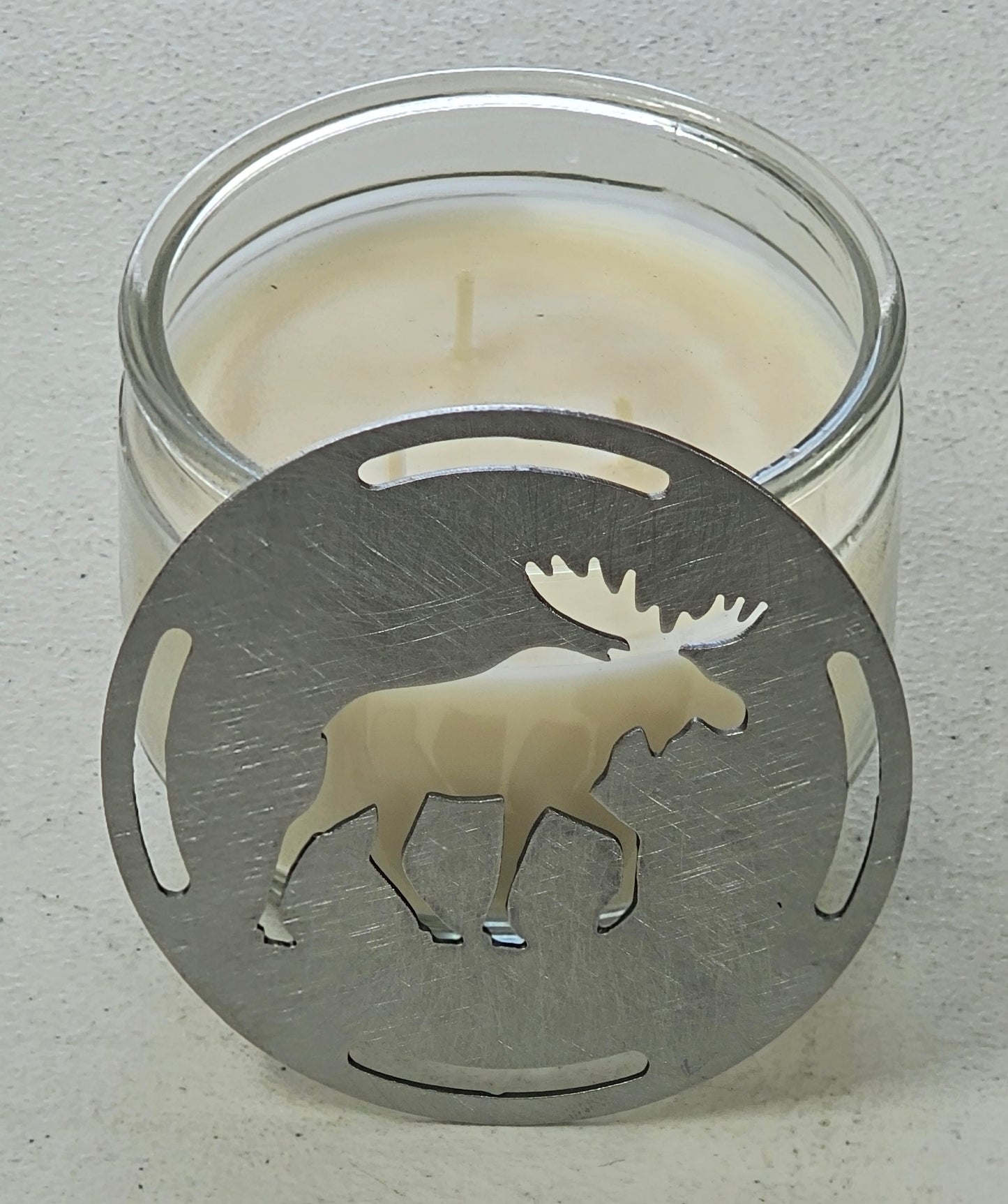 Flat metal moose candle topper next to jar candle, rustic woodland candle accessory