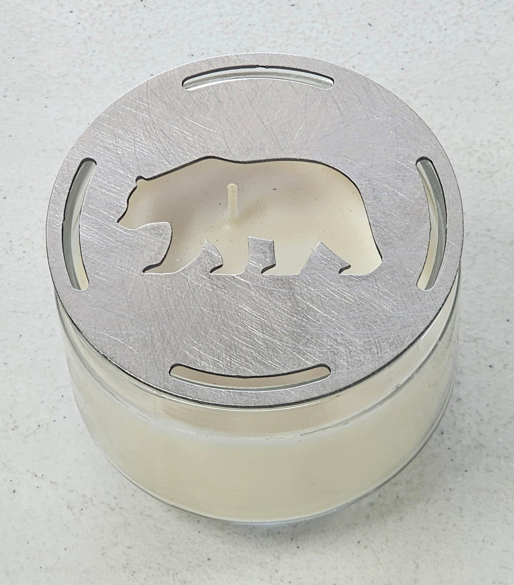 Rustic bear candle topper sitting flat on white jar candle showing wildlife silhouette design