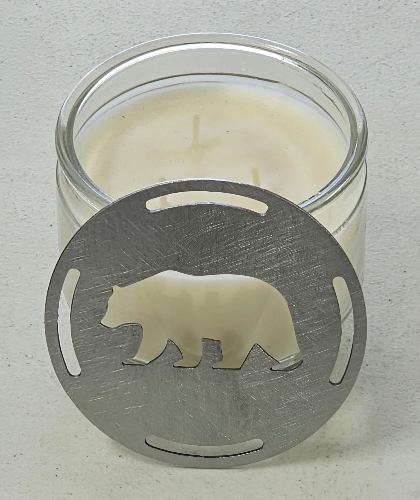 Rustic bear candle topper sitting flat on white jar candle showing wildlife silhouette design