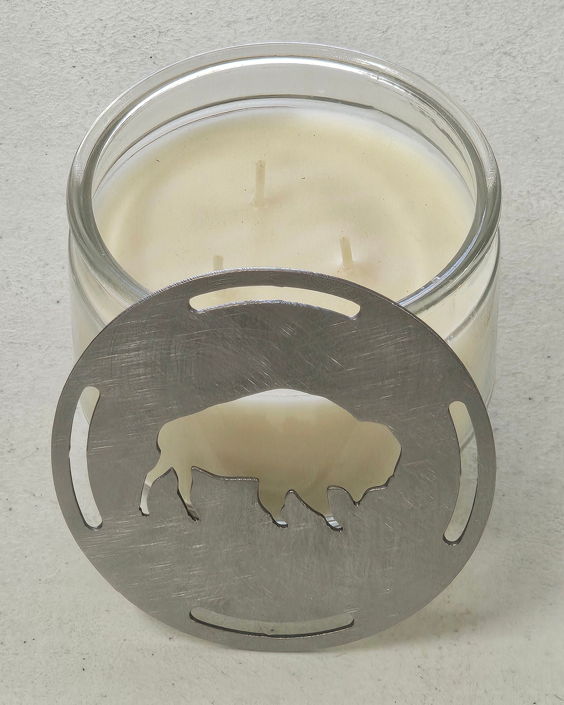 Buffalo candle topper steel lid sitting against a glass jar candle