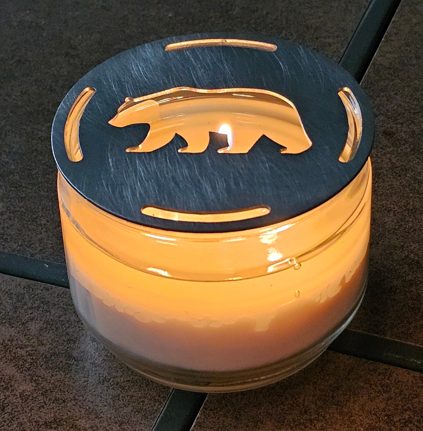 Rustic bear candle topper sitting flat on white jar candle showing wildlife silhouette design