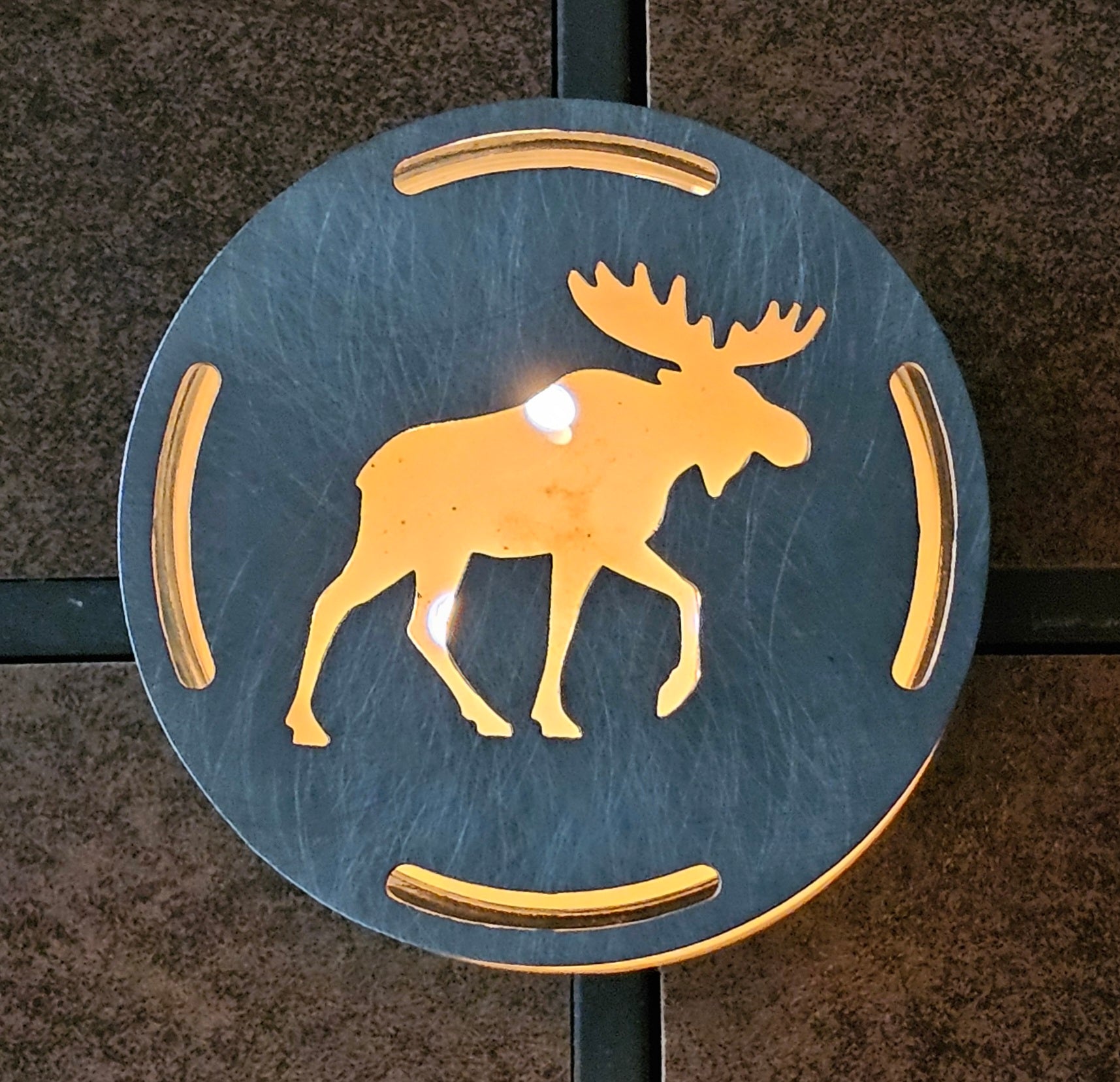 Moose candle topper on a lit jar candle creating a warm glowing silhouette, rustic cabin decor