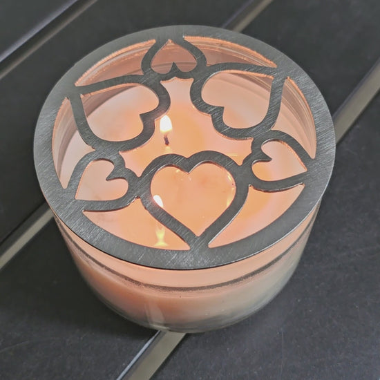 Tangled Hearts metal candle topper featuring intertwined heart design on a lit jar candle