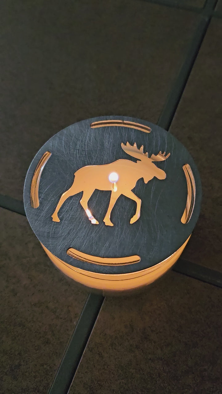 Moose candle topper on a lit jar candle creating a warm glowing silhouette, rustic cabin decor