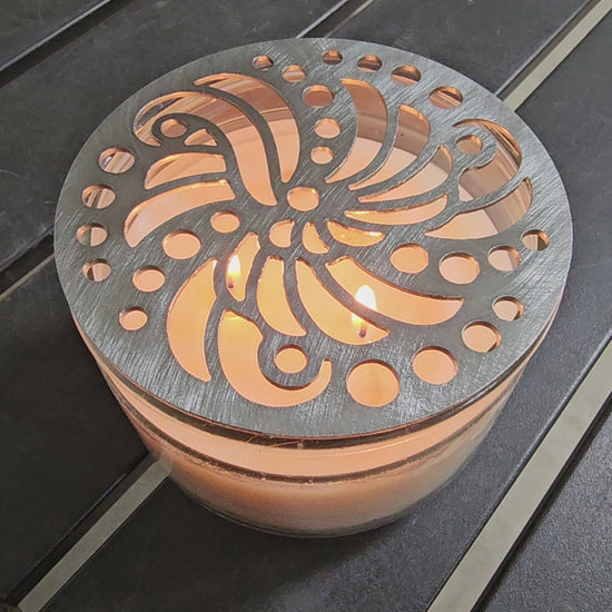 Luxury candle accessory with intricate cutout design casting soft light pattern.