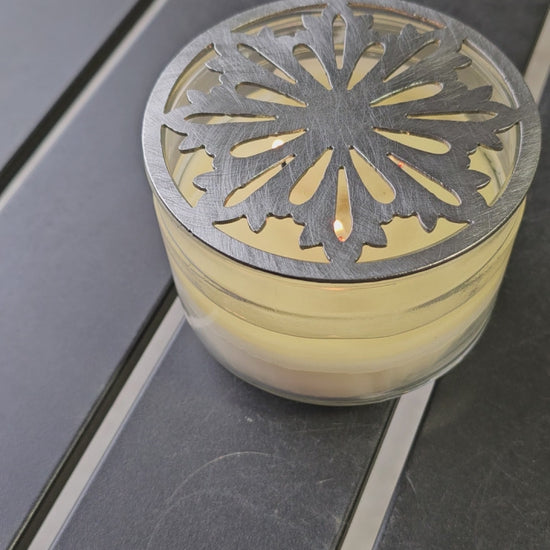 Nordic snowflake metal candle topper placed on white jar candle