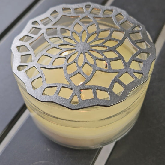 “Floral mandala metal candle topper on jar candle creating even burn and decorative light pattern”