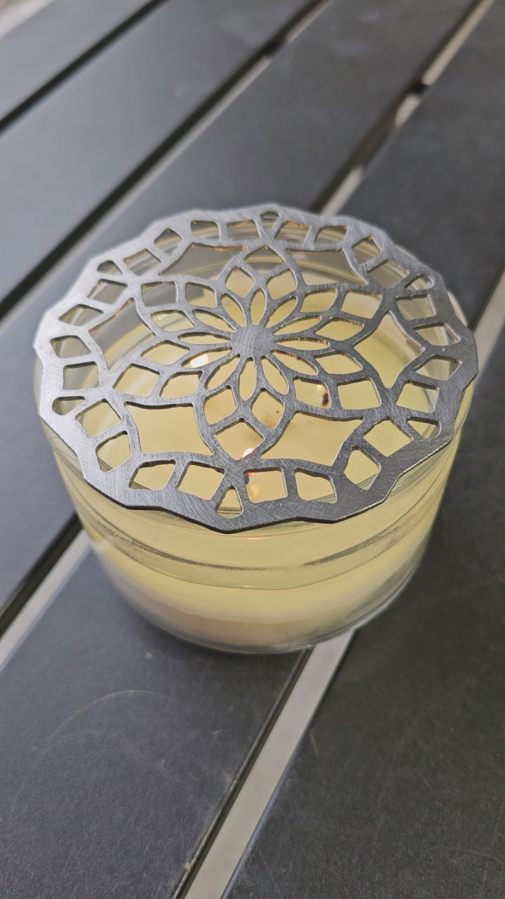 “Floral mandala metal candle topper on jar candle creating even burn and decorative light pattern”
